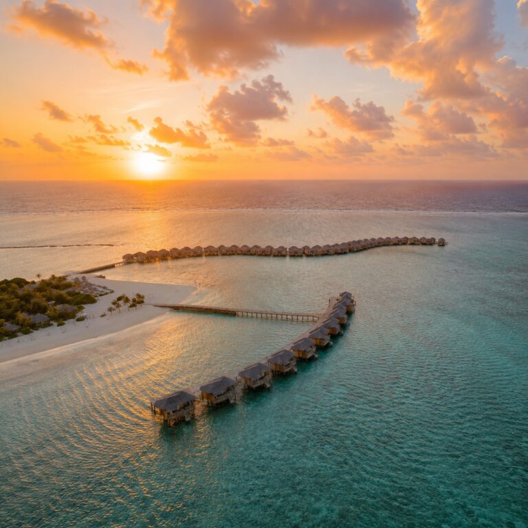 You & Me Maldives overwater villas surrounded by the Indian Ocean at sunset