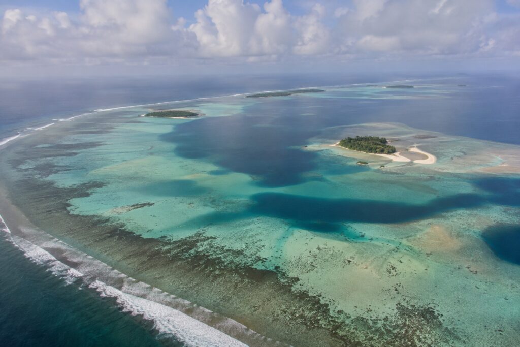 Aerial view of a natural Maldives atoll with coral reefs, lagoon, sandbanks and tropical islands